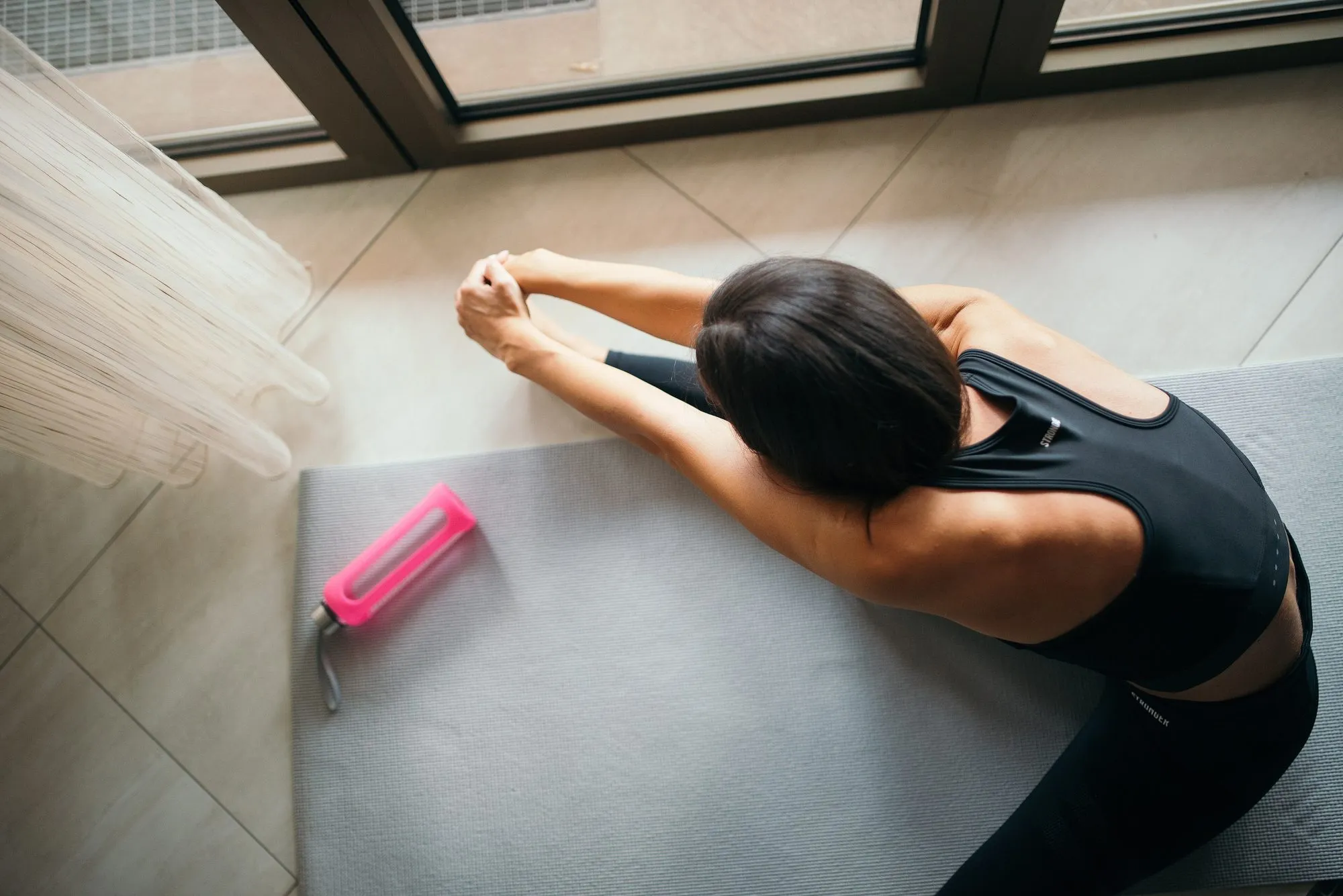 Frau dehnt sich auf einer grauen Yogamatte, von oben fotografiert