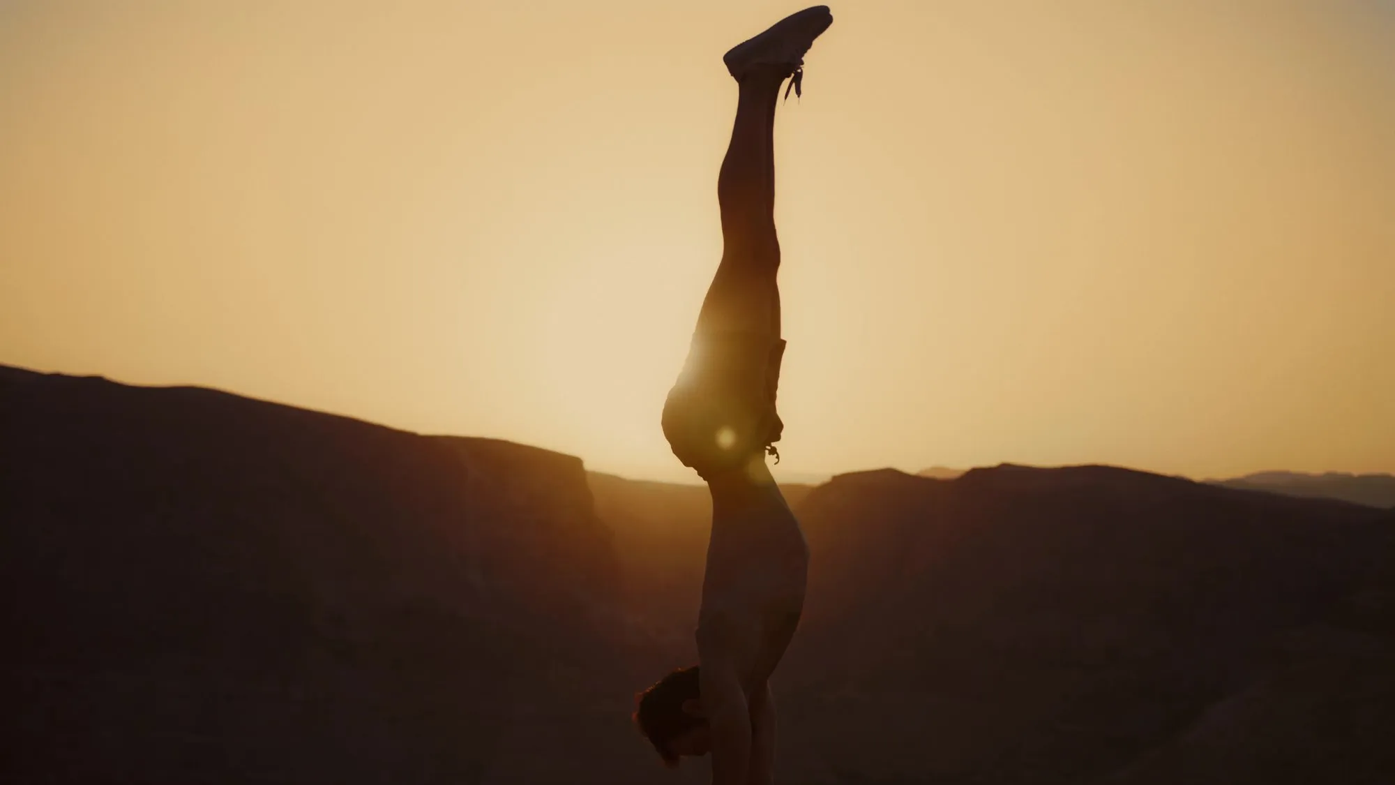 Silhouette einer Person im Handstand vor der untergehenden Sonne