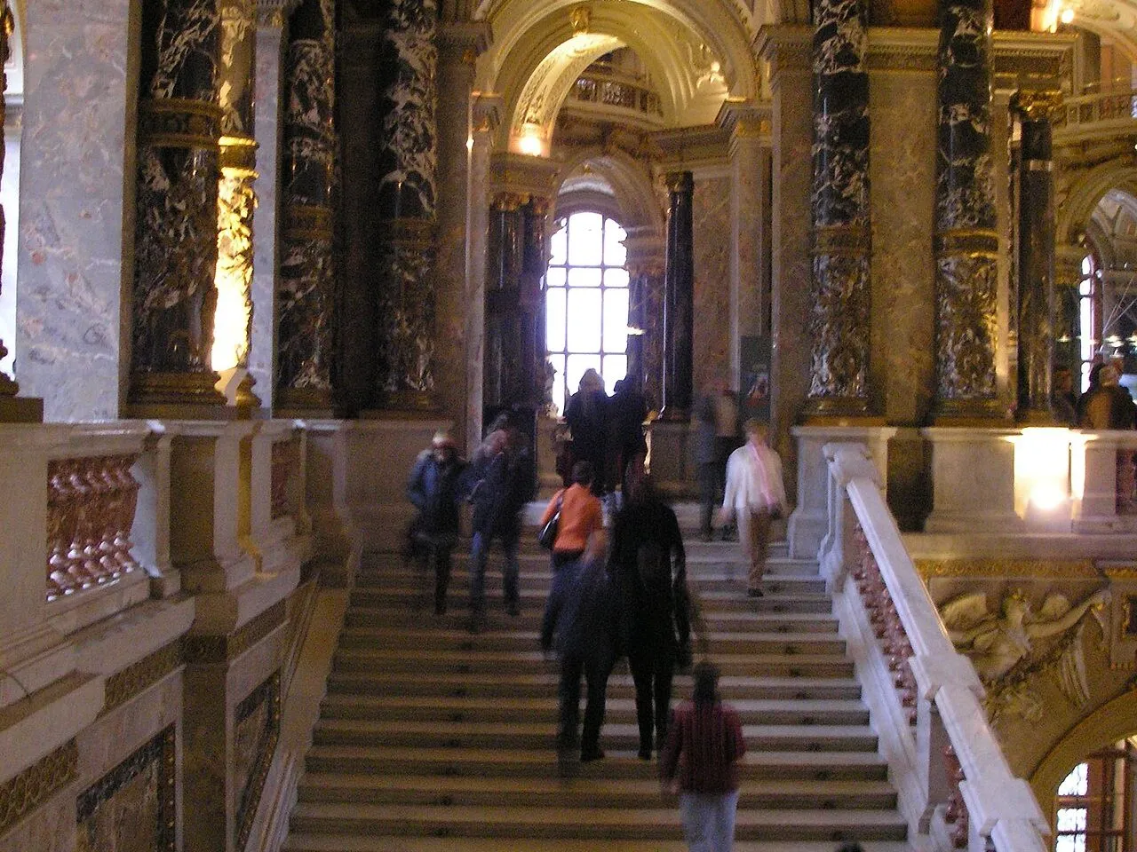 Besucherinnen und Besucher auf der prunkvollen Marmortreppe eines Wiener Museums